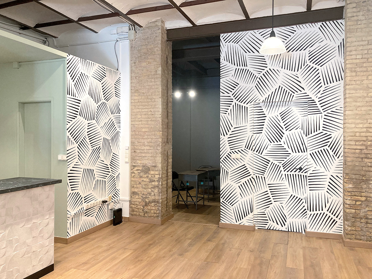 Light, abstract, geometric black and white indoor murals in a modern gallery space.
