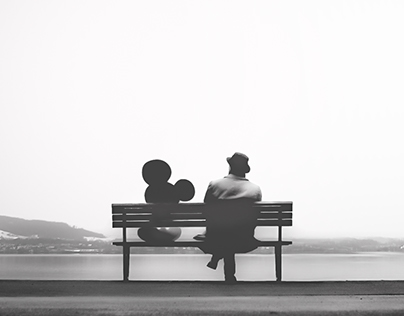 Walt Disney sitting on a bench talking with Mickey