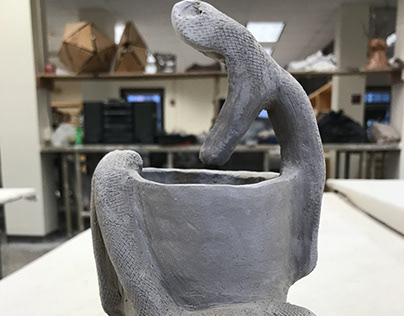Ceramic sculpture of a snake wrapped around cup