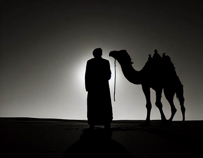 Man with his camel in the middle of the desert