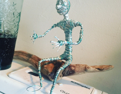 Wire man on driftwood.