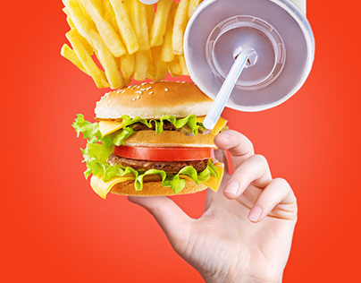 Hand with burger, French fries, ketchup and a drink