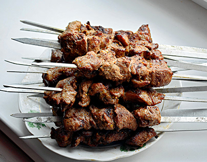 skewers are prepared on a barbecue grill over charcoal