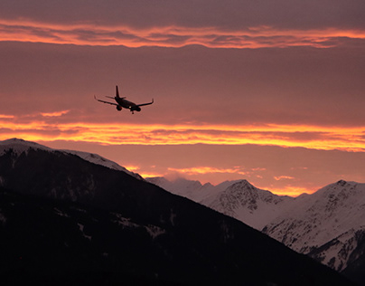 An airplane landing in the Alps during sunset